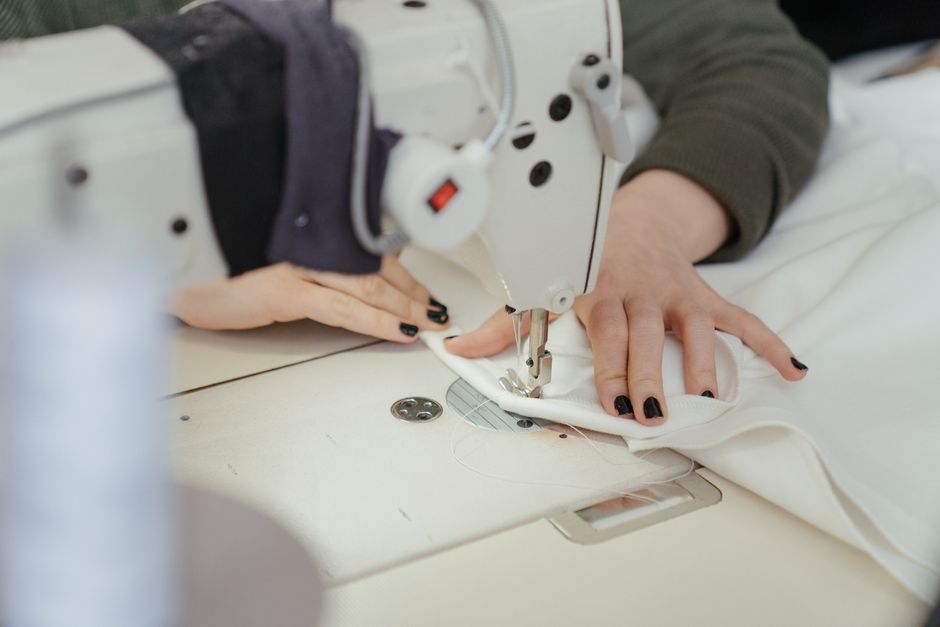 Close-up of hands sewing fabric on a professional sewing machine in a workshop.