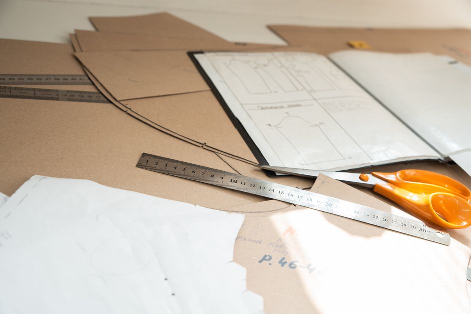 Close-up of a sewing workspace with paper patterns, rulers, and scissors.