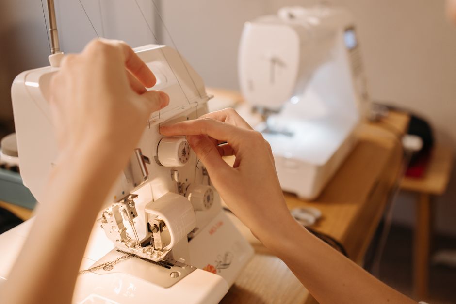 Hands adjusting knobs on a sewing machine for precise stitching. Perfect for sewing, crafting, or hobby-related visuals.